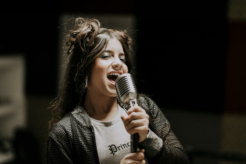 Woman in Black and White Sweater Holding Microphone
