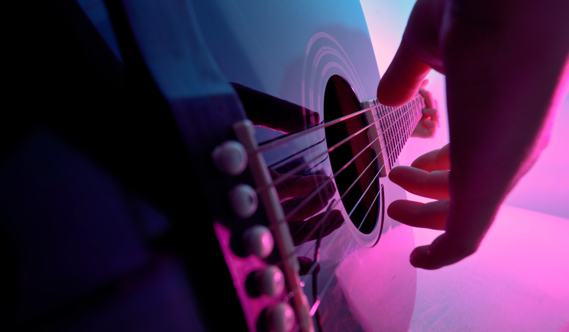 Acoustic guitar played by a girl and colorful lights